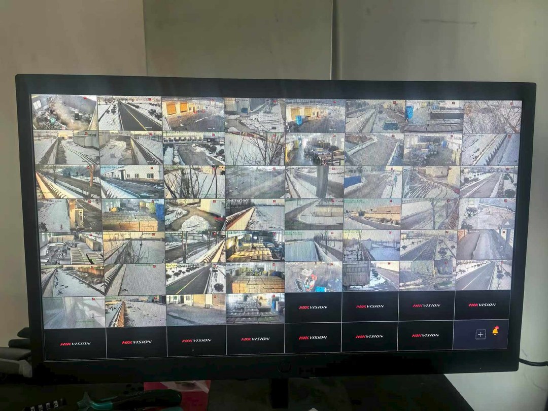 利辛县老乡鸡养殖基地监控中心大屏1：约50路实时画面拼接，覆盖厂区大门/消毒通道/饲料仓储/鸡舍/周界等全场景，背景雪景提示施工期间低温环境